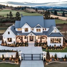 an aerial view of a large white house with christmas lights on the front and sides