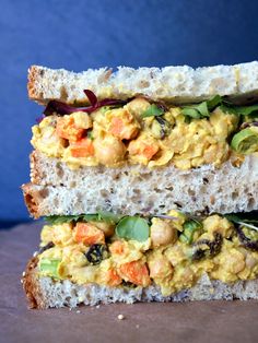 two pieces of bread stacked on top of each other with vegetables and chickpeas