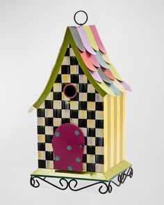 a colorful birdhouse with a pink chair in the front and a checkered roof