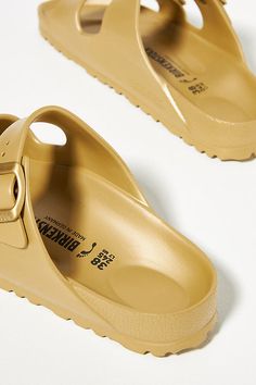 Rendered in a modern EVA finish, these sandals deliver a sporty update on the classic silhouette. You’re a shoe -in for incredible style and comfort when you slip on Birkenstock®. (P.S. it’s our favorite step when putting together an OOTD)! | Arizona EVA Sandals by Birkenstock in Gold, Women's, Size: 41 at Anthropologie Trendy Slip-on Slides With Arch Support, Modern Slides With Cushioned Footbed And Round Toe, Trendy Closed Toe Slides With Cushioned Footbed, Gold Slides With Leather Footbed, Gold Leather Footbed Slides, Trendy Cushioned Slide Sport Sandals, Trendy Sport Sandals With Cushioned Footbed, Trendy Slip-on Sport Sandals With Removable Insole, Trendy Slide Sport Sandals With Cushioned Footbed