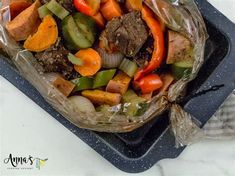 meat and vegetables wrapped in plastic sitting on top of a grilling pan, ready to be cooked