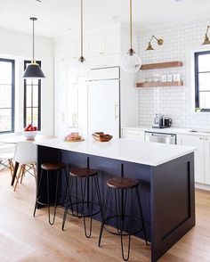 a kitchen island with three stools in front of it