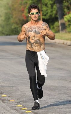 a shirtless man running down the street wearing headphones and sunglasses on his face