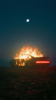 a car on fire with the moon in the background