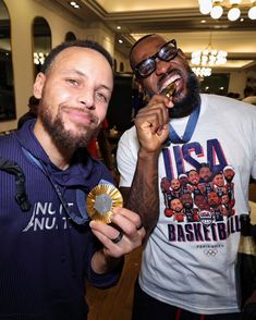 two men standing next to each other holding medals