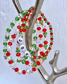 a christmas ornament is hanging on a tree branch with red, green and white beads