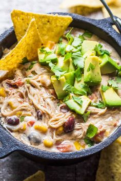 a bowl of chicken tortilla soup with avocado and cilantro