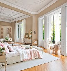 an elegant bedroom with white furniture and wood flooring, along with french doors leading to the outside