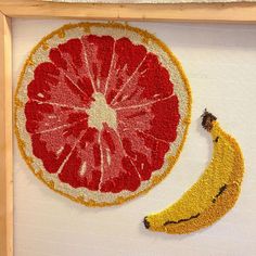 a piece of fruit with a banana on it is in a wooden frame and hanging on the wall