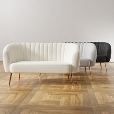 three white and black couches sitting on top of a wooden floor next to each other