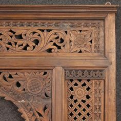 an intricate carved wooden panel with flowers and leaves on the top, along with other decorative elements