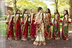 a group of women standing next to each other wearing red and green dresses with gold trims