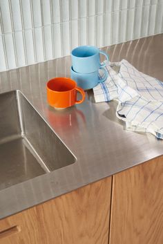 a kitchen sink with two mugs on it