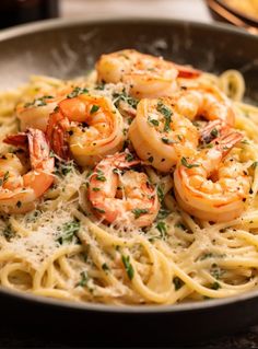 pasta with shrimp and parmesan cheese in a skillet on a wooden table