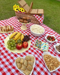 a picnic table filled with food and snacks on it's side, including apples, grapes, bananas, strawberries, crackers