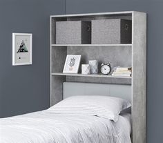 a white bed sitting under a gray wall next to a book shelf filled with books