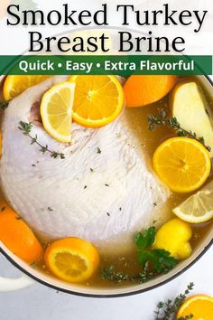 a pan filled with chicken and lemons on top of a white counter next to sliced oranges