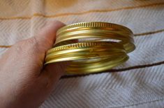 a person is holding three gold rings in their left hand and the other two are stacked on top of each other