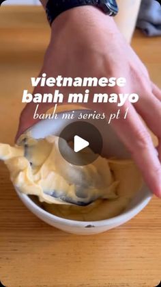 a person holding a spoon in a bowl with food on it and the words vietnamese banh mi mayo written below