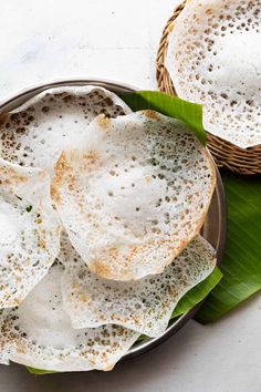 two baskets filled with fried food on top of a green leaf