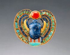 an egyptian scar with blue and gold designs on the front, red stone in the center