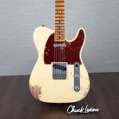 an old white guitar sitting on top of a wooden table