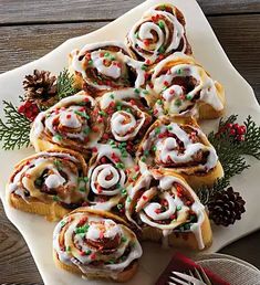 a white plate topped with pastry covered in frosting and sprinkles next to pine cones