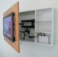 a tv mounted to the side of a white wall next to a wooden framed object