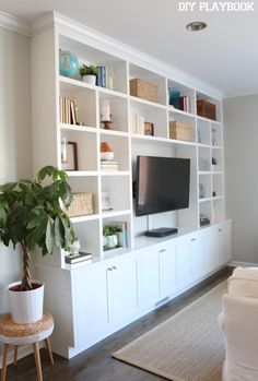 a living room filled with furniture and a flat screen tv on top of a white bookcase