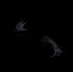 a person in the dark with their hands out and one hand extended up to the ground