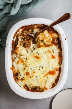 a casserole dish with cheese and mushrooms in it next to a glass of milk