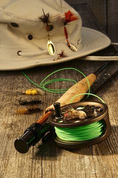 a fishing rod, reel and hat on a wooden table with other fishing gear in the background