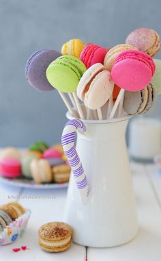 a cup full of colorful macaroons sitting on top of a table