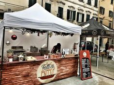 an outdoor food stand with tables and umbrellas