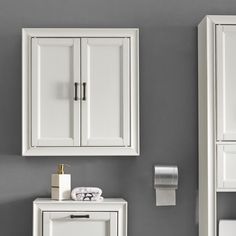 a bathroom with two white cabinets and a towel dispenser on the wall