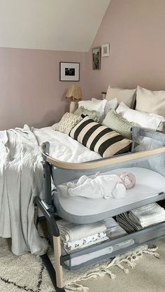 a baby crib in the corner of a bedroom with pink walls and white bedding