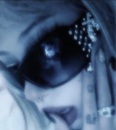 a close up of a person wearing sunglasses and holding their hand to her face with both hands