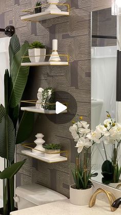 the bathroom is decorated with white flowers and greenery in vases on shelving