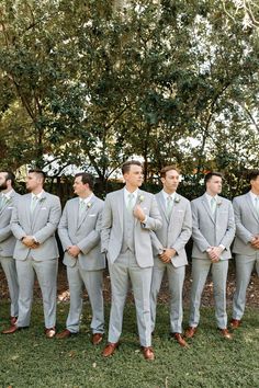 a group of men standing next to each other in front of some trees and grass