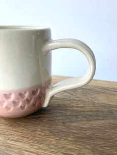 a white and pink coffee cup sitting on top of a wooden table