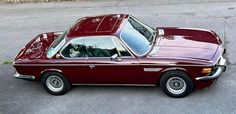 an old maroon car is parked on the street