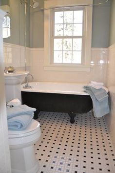 a black and white bathtub sitting next to a toilet in a bathroom under a window