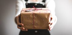 a woman is holding a wrapped present in her hands with a red string on it