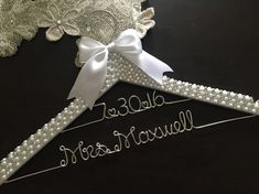 two wedding garters with white ribbons and pearls on them, one is for bride and the other is for groom