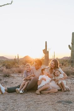 a family sitting on the ground in front of a cactus