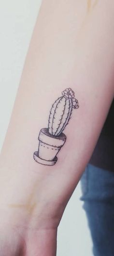 a small cactus tattoo on the left inner forearm and wrist, with a potted plant in it