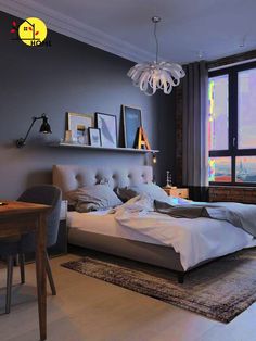 a bedroom with a bed, desk and chair in front of a large window overlooking the city