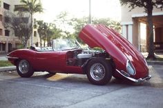 an old red sports car with its hood open