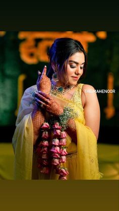 a woman in a yellow sari holding a flower garland with her hands and face