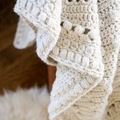 a white crocheted blanket on top of a wooden chair